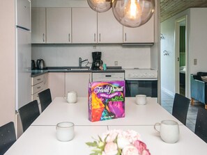 A modern kitchen with white cabinets, a coffee maker, and a box of TriViAl Pursuit GENUS-UDGAVE. - 8 Person Holiday Home in Orsted (Ørsted)