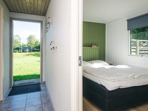 A bedroom with a bed, a green wall, a window, and a door leading outside. - 8 Person Holiday Home in Orsted (Ørsted)