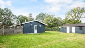 A fenced property with a single blue building, a smaller attached structure, and a well-maintained lawn.
