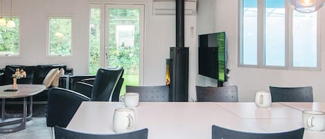 A modern interior with a dining area, black chairs, a table, a fireplace, and large windows.