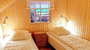 A room with two single beds, a small wooden nightstand, and a window with a view of the outside. - 5 Person Holiday Home in Lammhult, Sverige (Lammhult)
