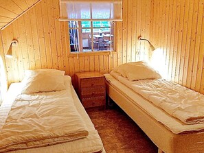 A room with two single beds, a small wooden nightstand, and a window with a view of the outside. - 5 Person Holiday Home in Lammhult, Sverige (Lammhult)