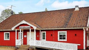 A red building with a white porch and a sign reading 'BYDEGÅRD'. - 5 Person Holiday Home in Lammhult, Sverige (Lammhult)