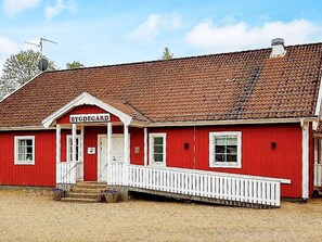 A red building with a white porch and a sign reading 'BYDEGÅRD'. - 5 Person Holiday Home in Lammhult, Sverige (Lammhult)