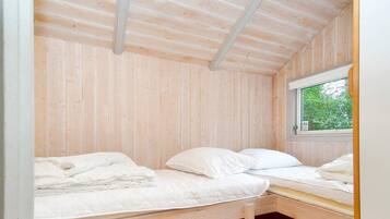 A small, single-bed room with wooden walls and a window.