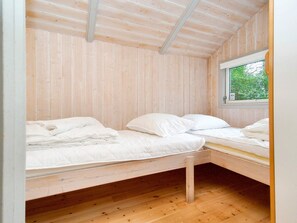 Ein kleines Zimmer mit einem Einzelbett, Holzwänden und einem Fenster.