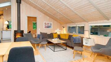 A cozy living room with a fireplace, wooden walls, and a dining area.