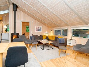 Tunnelmallinen olohuone, jossa on takka, puuseinät ja ruokailutila.