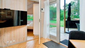 A room with a television, a sliding glass door leading to an outdoor area with a table and chairs. - 8 Person Holiday Home in Melby (Melby)