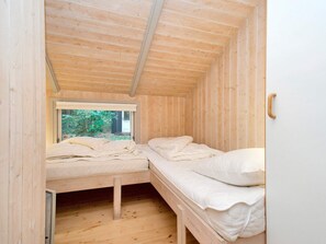 Una habitación de madera pequeña con dos camas, una ventana y una puerta.