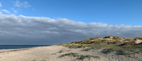 Une plage avec des dunes de sable et un ciel dégagé.