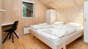 A bedroom with a wooden floor, a bed with white bedding, a desk with a chair, and a wardrobe. - 8 Person Holiday Home in Melby (Melby)