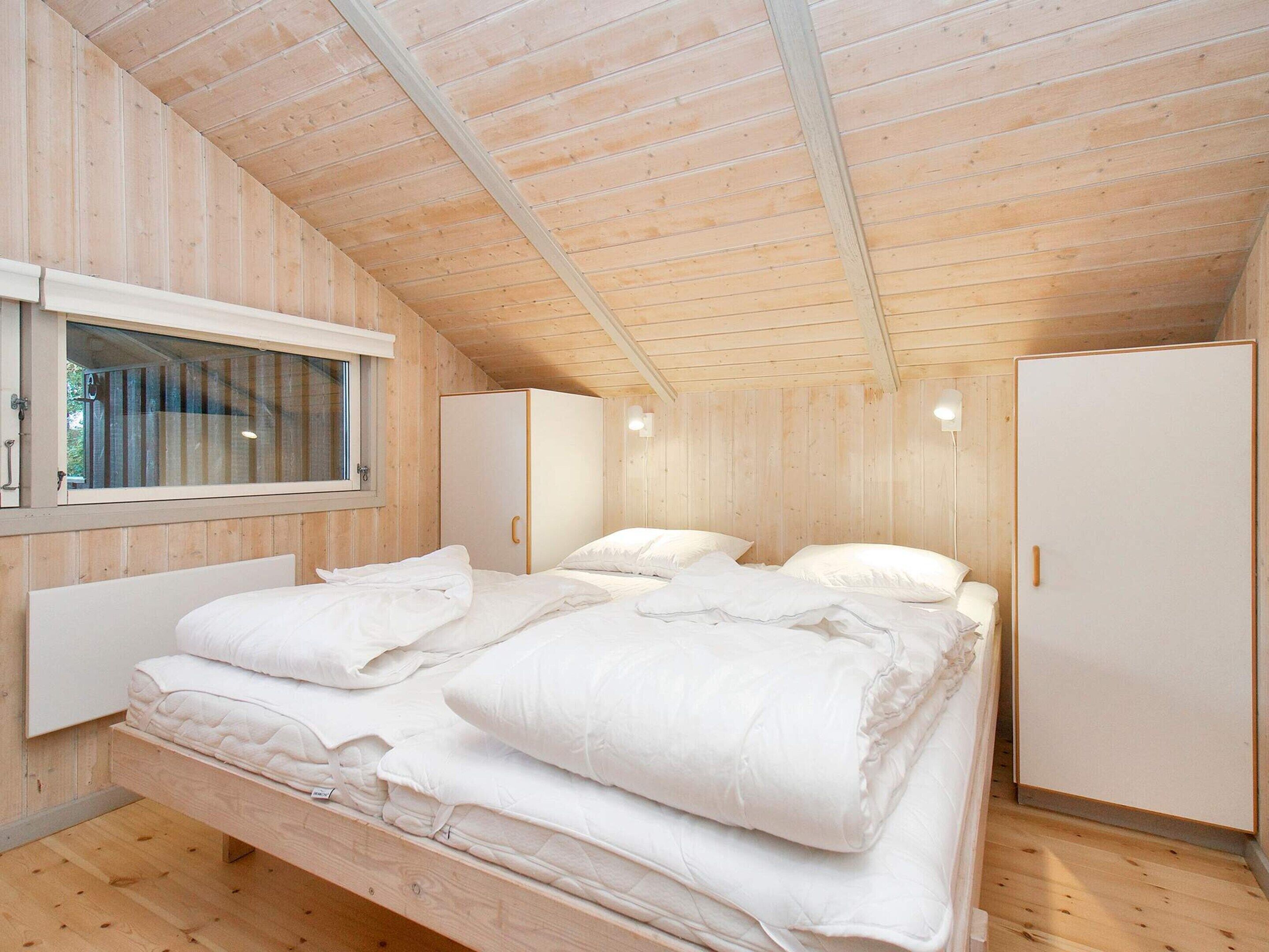 A wooden-paneled room with a bed, a wardrobe, and a window.