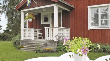 A red wooden house with a white porch and a flag.