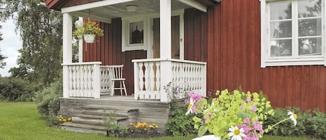 A red wooden house with a white porch and a flag.