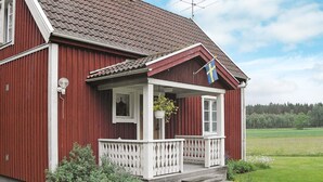 Et rødt træhus med en hvid veranda og et flag.