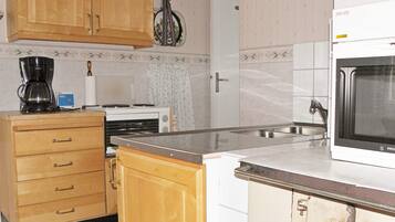 A kitchen with wooden cabinets, a coffee maker, a microwave, and a tiled backsplash.