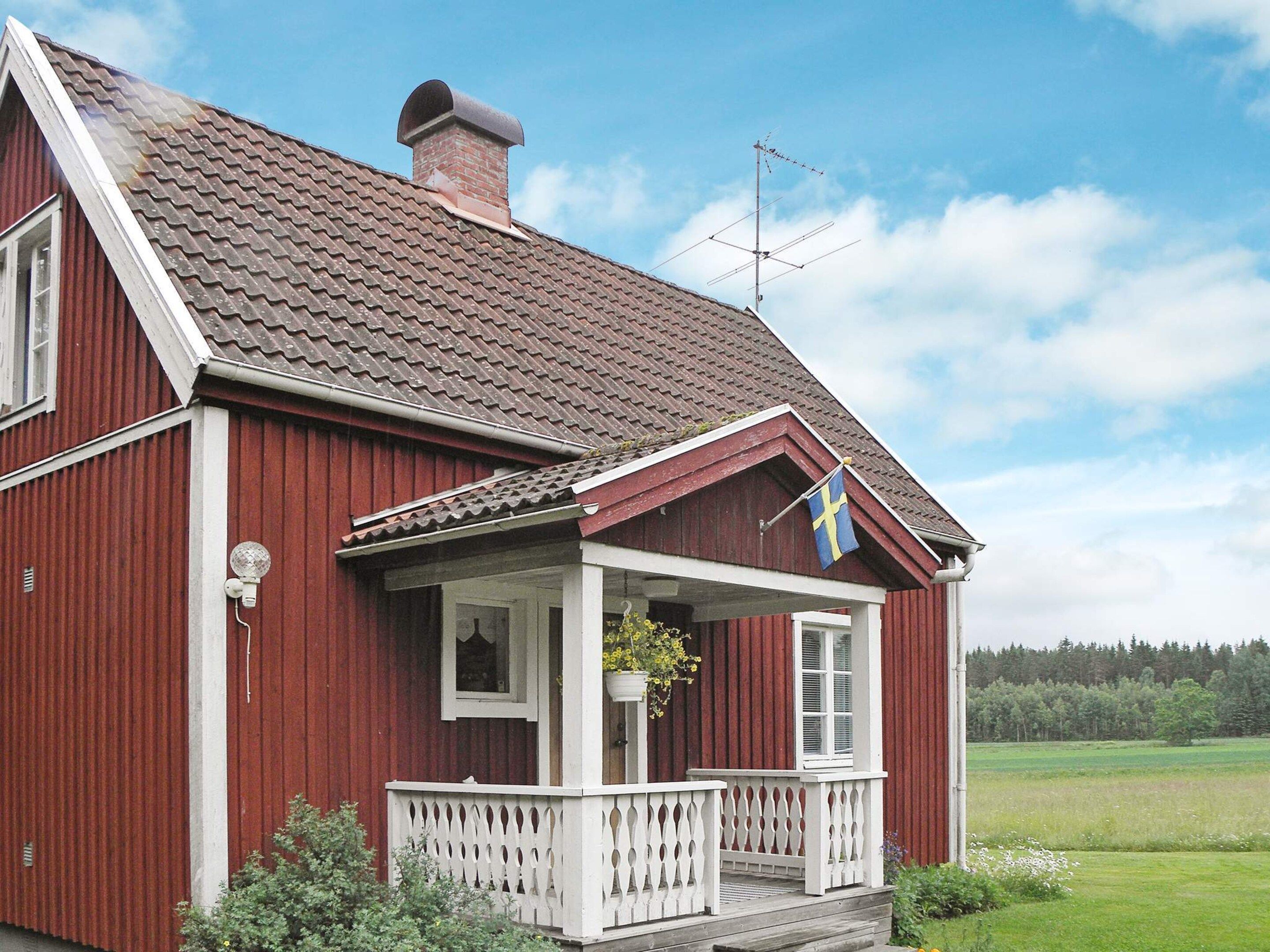 A red wooden house with a white porch and a flag.