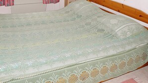 A bed with a patterned bedspread, a wicker chair, and a wall-mounted lamp. - 4 Person Holiday Home in Gullspang (Gullspång)