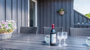 An outdoor patio with a table set for two, a bottle of wine, and two glasses. - 4 Star Holiday Home in Haderslev (Haderslev)