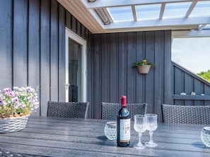 An outdoor patio with a table set for two, a bottle of wine, and two glasses.