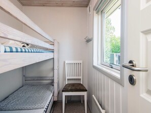 A small room with bunk beds, a white chair, a radiator, and a window with a view of greenery. - 4 Star Holiday Home in Haderslev (Haderslev)