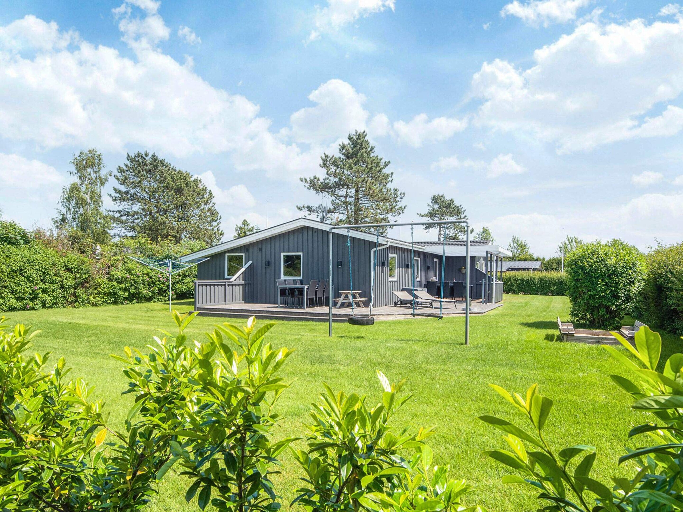 Een modern huis met een terras, buitenmeubels en een schommel.
