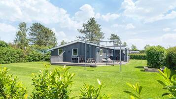Een modern huis met een terras, buitenmeubels en een schommel.