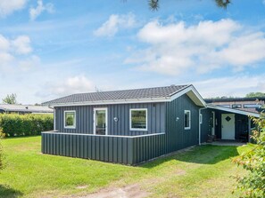 A single-story mobile home with a flat roof, a front porch, and a small attached garage.