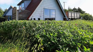 A house with a steeply pitched roof, a chimney, and a large window. - Lovely Holiday Home in Lemvig with Hot Tub (Lemvig)