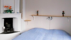 A bedroom with a bed, a fireplace, and two wall-mounted shelves with flowers. - 6 Person Holiday Home in Ryssby (Ryssby)