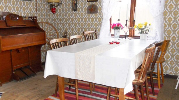 A dining area with a long table, chairs, a piano, and a patterned wallpaper. - 6 Person Holiday Home in Ryssby (Ryssby)