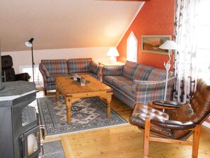 A cozy living room with a sofa, a coffee table, a fireplace, and a leather armchair. - 6 Person Holiday Home in Ryssby (Ryssby)