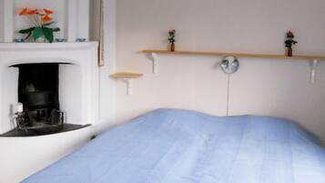 A bedroom with a bed, a fireplace, and two wall-mounted shelves with small vases.
