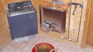 A sauna with a metal container for water, a wooden bucket, and a metal heater. - 6 Person Holiday Home in Arboga-by Traum (Arboga)