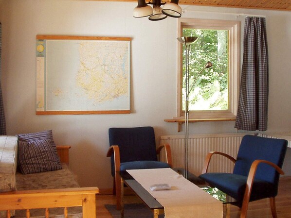 Un salon chaleureux avec une carte accrochée au mur, une table en bois et deux chaises bleues.