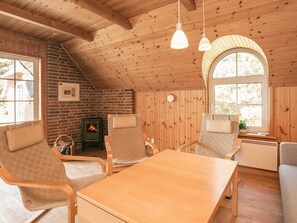 Una habitación acogedora con techo de madera, chimenea de ladrillo y un amplio ventanal.
