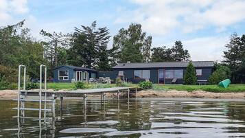 A lakeside property with a dock, two cabins, and a grassy area.