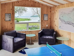 A room with two leather chairs, a ping pong table, and a large window overlooking a lake. - Spacious Holiday Home in Storvorde With Sea Nearby (Skanderborg)