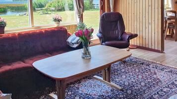 A cozy room with a wooden table, a cushioned bench, and a view of a lake.