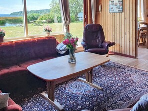 A cozy room with a wooden table, a cushioned bench, and a view of a lake.
