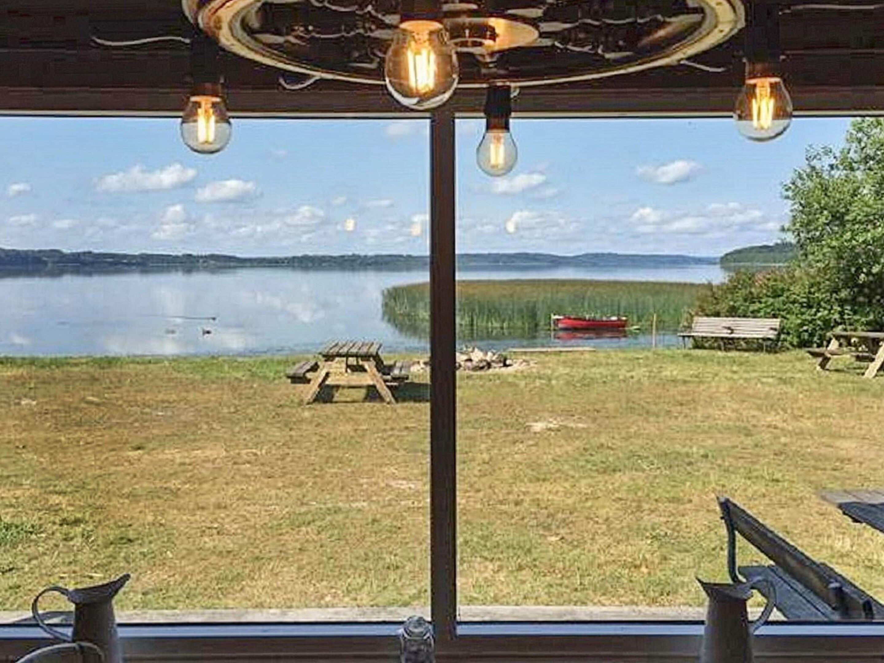 A lakeside view from a cabin with a wooden deck, picnic table, and a boat in the distance.