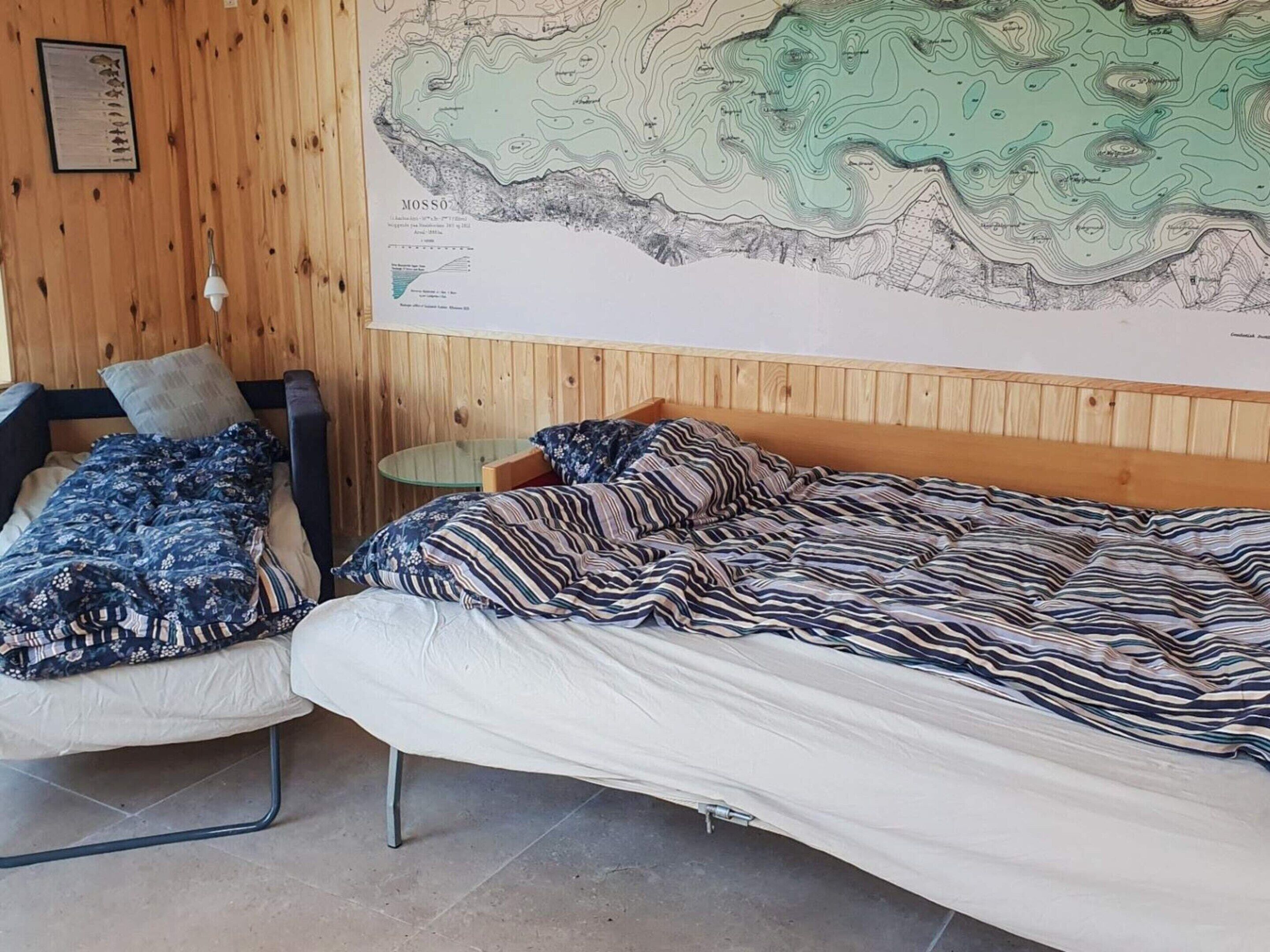 Une chambre avec deux lits, un mur en bois et une grande carte accrochée au mur.