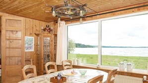 Interior de fusta amb taula de menjador, cadires, vista d'un llac i un ventilador de sostre.