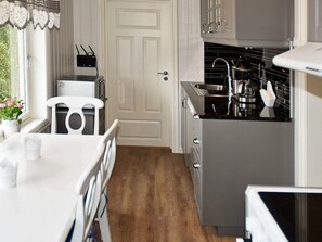 A kitchen with a white countertop, a sink, and a stove. There is a window with a view of greenery outside. - Holiday Home in MÃ¥ndalen (Rauma)