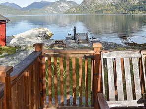 Een houten terras met uitzicht op een meer en bergen.