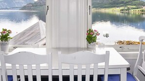 Ein weißer Tisch mit Stühlen, Blick auf einen See und Berge im Hintergrund.