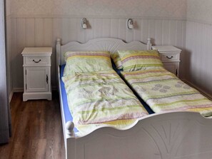 A bed with a patterned bedspread, two bedside tables, and a nightstand with a drawer. - Holiday Home in MÃ¥ndalen (Rauma)