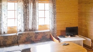 A living room with a sofa, a small table, and a television. - 5 Person Holiday Home in Engavagen (Meloy)