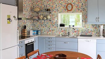 Una cocina con un salpicadero floral, un reloj y una ventana.